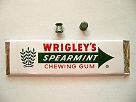 A  .177 caliber "Wadcutter" pellet next to a stick of chewing gum.